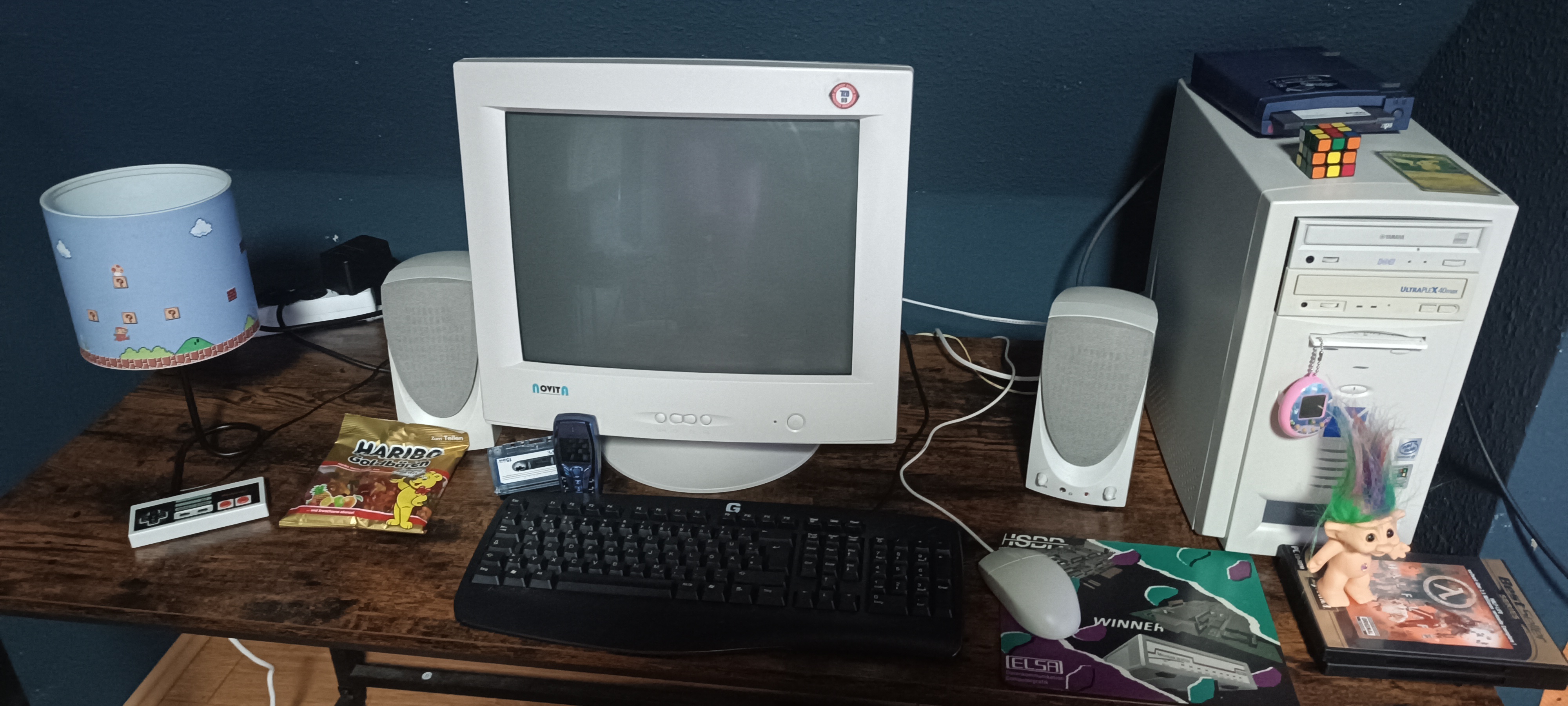 A CRT-era desktop computer setup with monitor, speakers, and old media.